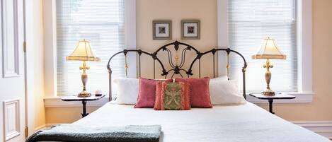Un lit bien fait, recouvert d’une couette blanche, avec deux tables de chevet dotées de lampes et une tête de lit décorative.
