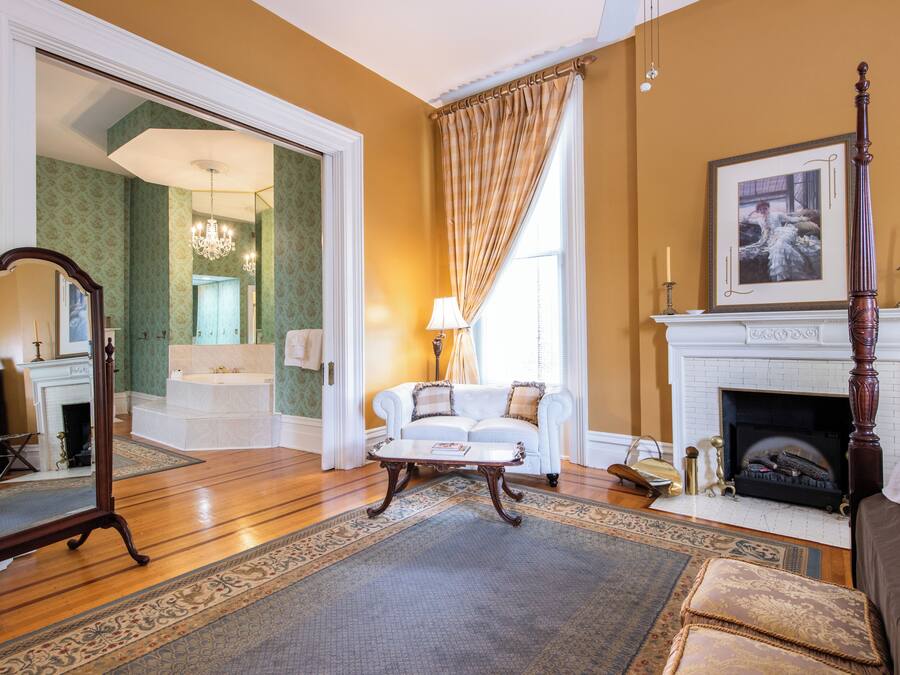 Un salon avec un canapé blanc, une cheminée, un miroir et un lustre.