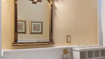 A bathroom with a white sink, gold faucets, a gold-framed mirror, and a toilet.