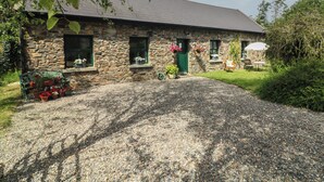 Un bâtiment en pierre avec une allée de gravier, une porte verte et des fenêtres ornées de jardinières.