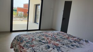A bedroom with a bed, a sliding glass door, and a door. - VILLA REVA with swimming pool, between land and sea (Nézignan-l'Évêque)