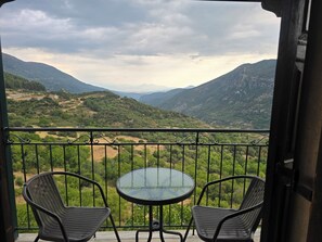Un balcon avec deux chaises et une table, donnant sur un paysage montagneux.