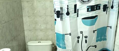 A bathroom with a toilet, a sink, and a shower curtain with a kitchen-themed design.