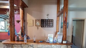Een bar met stenen details, een houten plafond, ingelijste foto's en een klein plankje met spullen.