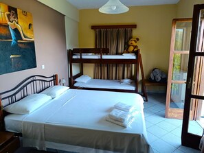 Una habitación con literas, una cama grande, un cuadro en la pared y una ventana con cortinas.
