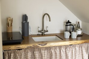 A kitchen with a sink, a coffee maker, and a jar.