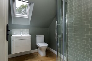 Un baño con inodoro blanco, lavamanos y cabina de ducha con puertas de vidrio.