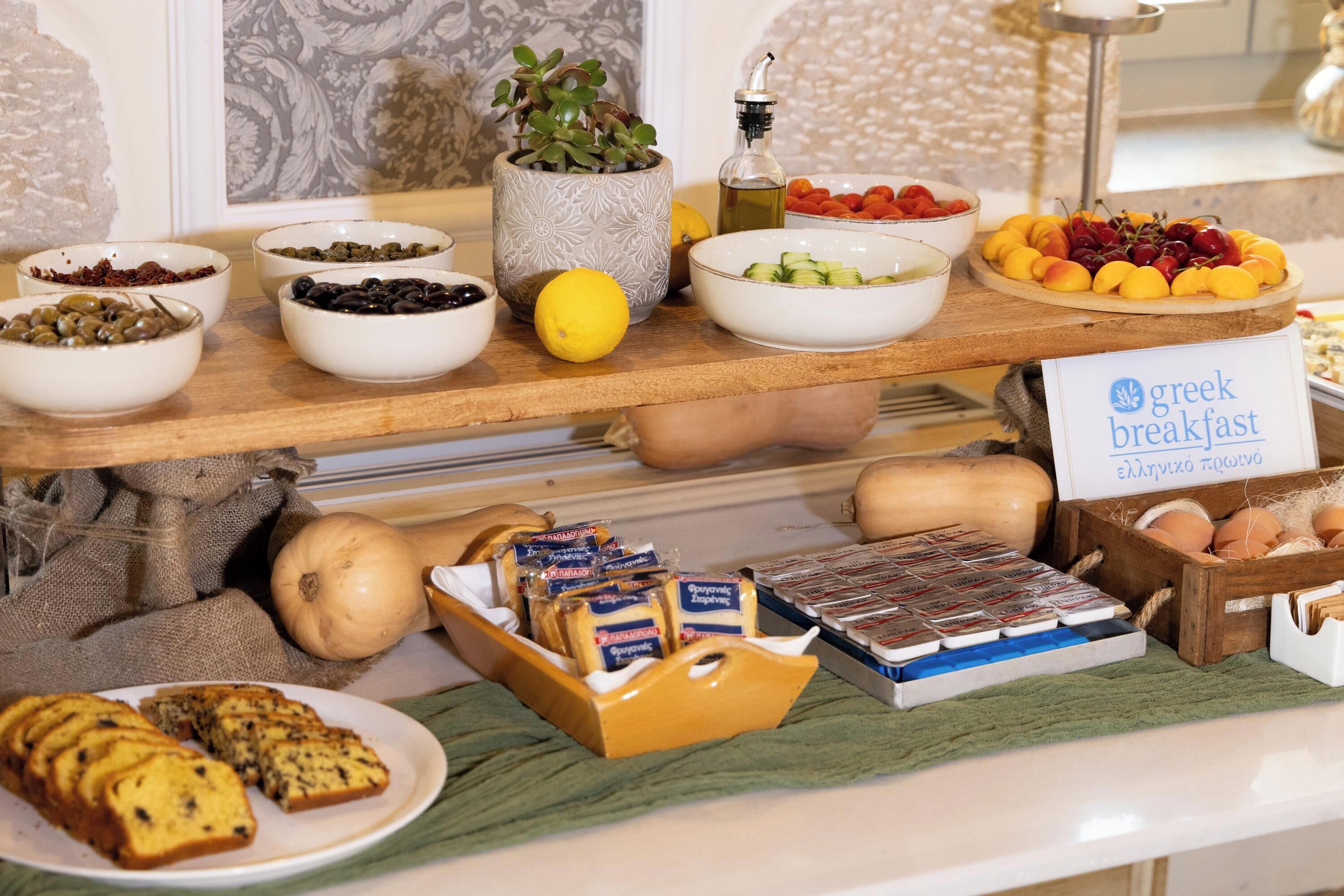 Ein Frühstücksbuffet mit verschiedenen Speisen und einem Schild mit der Aufschrift 'Griechisches Frühstück'.