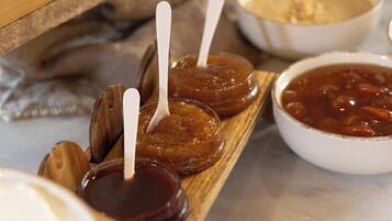 A wooden tray with jars of preserves and a bowl of soup.