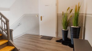 Una escalera que lleva a una puerta con la leyenda 'FeWo 5', con dos macetas a un lado.