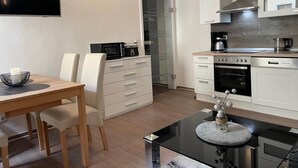 Una cocina moderna con armarios blancos, microondas, cafetera y un comedor con mesa y sillas.