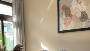 A modern living room with a grey sofa, a vase with dried plants, and a framed abstract painting on the wall. - Stylish apartment in the Gründerzeit district (Chemnitz)