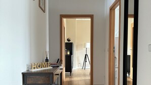 A hallway with wooden flooring, a desk with a lamp, framed pictures on the wall, and a mirror. - Stylish apartment in the Gründerzeit district (Chemnitz)
