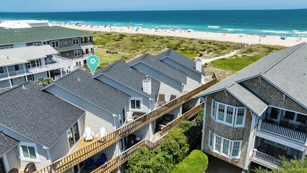 A coastal residential area with multiple houses, a wooden deck, and a view of the beach. - Ocean Views, Beach Access, Luxury Townhouse - Sleeps 10, Ping Pong! (Wrightsville Beach)