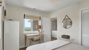 A bedroom with a bed, a desk with a chair, a window with a view, a mirror, and a wardrobe. - Ocean Views, Beach Access, Luxury Townhouse - Sleeps 10, Ping Pong! (Wrightsville Beach)