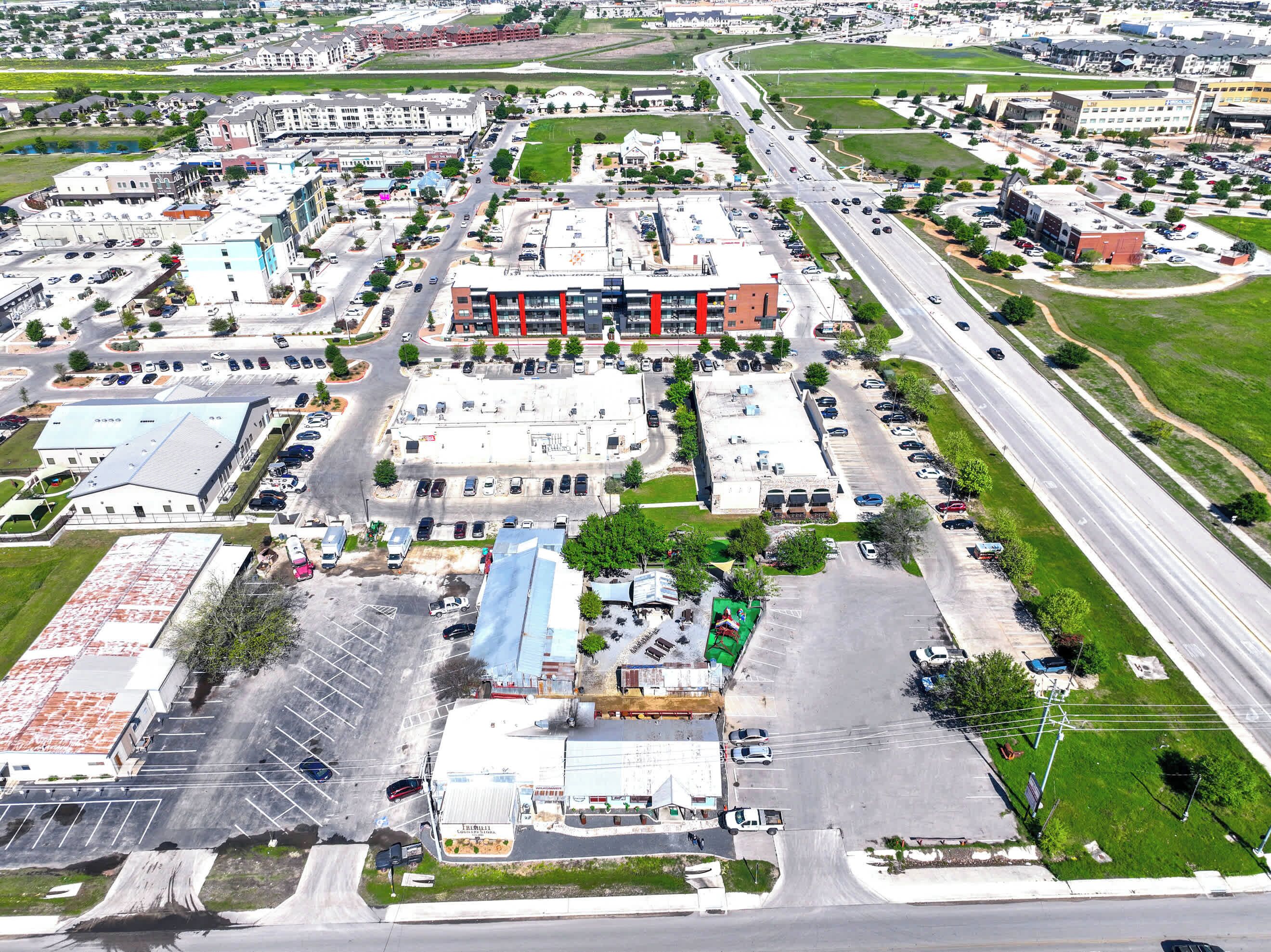 An aerial view of a commercial area with multiple buildings, parking lots, and roads.