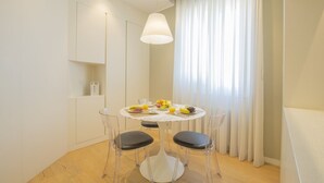 Un espace repas moderne avec une table ronde, quatre chaises et un luminaire suspendu.