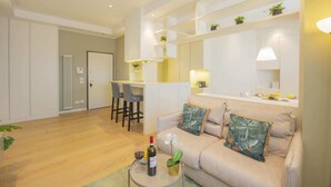 Un salon moderne avec un canapé, une table basse sur laquelle se trouvent une bouteille et un verre, et un coin repas avec des chaises et une table.