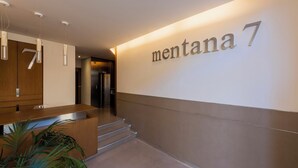 A modern hotel lobby with a reception desk, a staircase, and a wall displaying the name 'montana 7'. - Sweett | Mentana IV - Two Bedroom Apartment, Sleeps 3 (Milano)