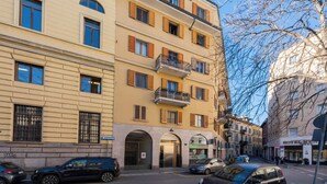A multi-story building with a ground-level entrance, balconies, and a visible shop on the ground floor. - Sweett | Mentana IV - Two Bedroom Apartment, Sleeps 3 (Milano)