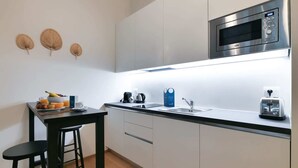 A modern kitchen with a microwave, sink, and coffee maker. There is a small dining area with a table and two chairs.