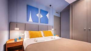 A hotel room with a bed, nightstands, a wardrobe, and two abstract wall art pieces. - Sweett | Roma 3B - One Bedroom Apartment, Sleeps 4 (Barcelona)