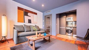 A modern living room with a grey sofa, a wooden coffee table, and a large abstract painting on the wall. - Sweett | Roma 3B - One Bedroom Apartment, Sleeps 4 (Barcelona)