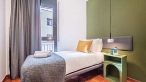 Hotellihuone, jossa on sänky, yöpöytä, lamppu ja näkymä ulos.