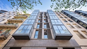 A modern high-rise building with a symmetrical facade, large windows, and a central atrium. - Sweett | Roma 5B - One Bedroom Apartment, Sleeps 4 (Barcelona)