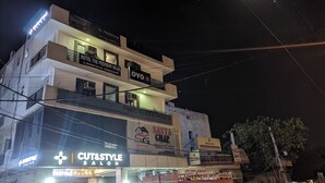 Un immeuble à plusieurs étages abritant divers commerces, notamment un hôtel appelé « Hotel The Premium Villa » et un salon de coiffure appelé « Cut & Style Salon ».