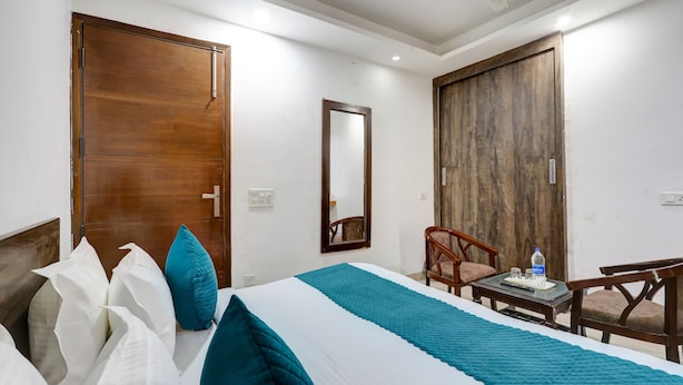Une chambre d’hôtel avec un lit, un bureau, une chaise et un grand miroir.