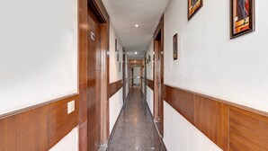 Un long couloir étroit, avec des portes en bois et des murs blancs, qui mène à une pièce au fond.