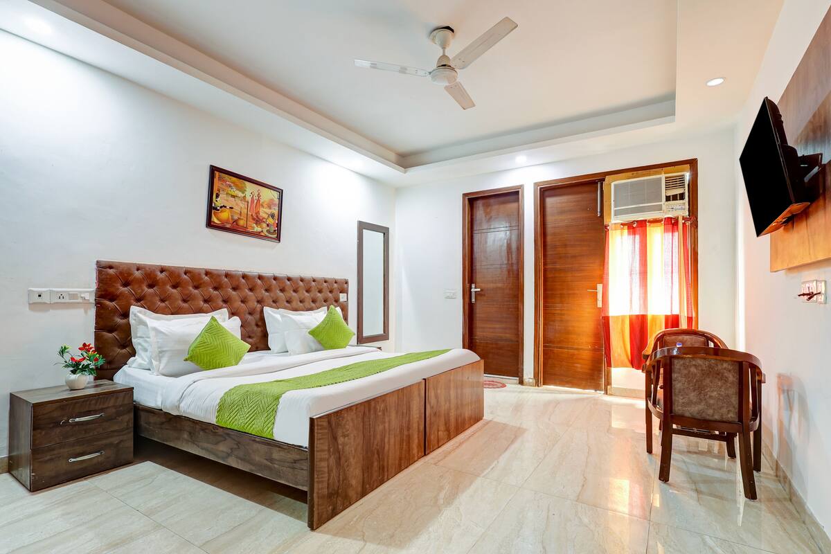 A bedroom with a bed, bedside table, nightstand, and a chair.