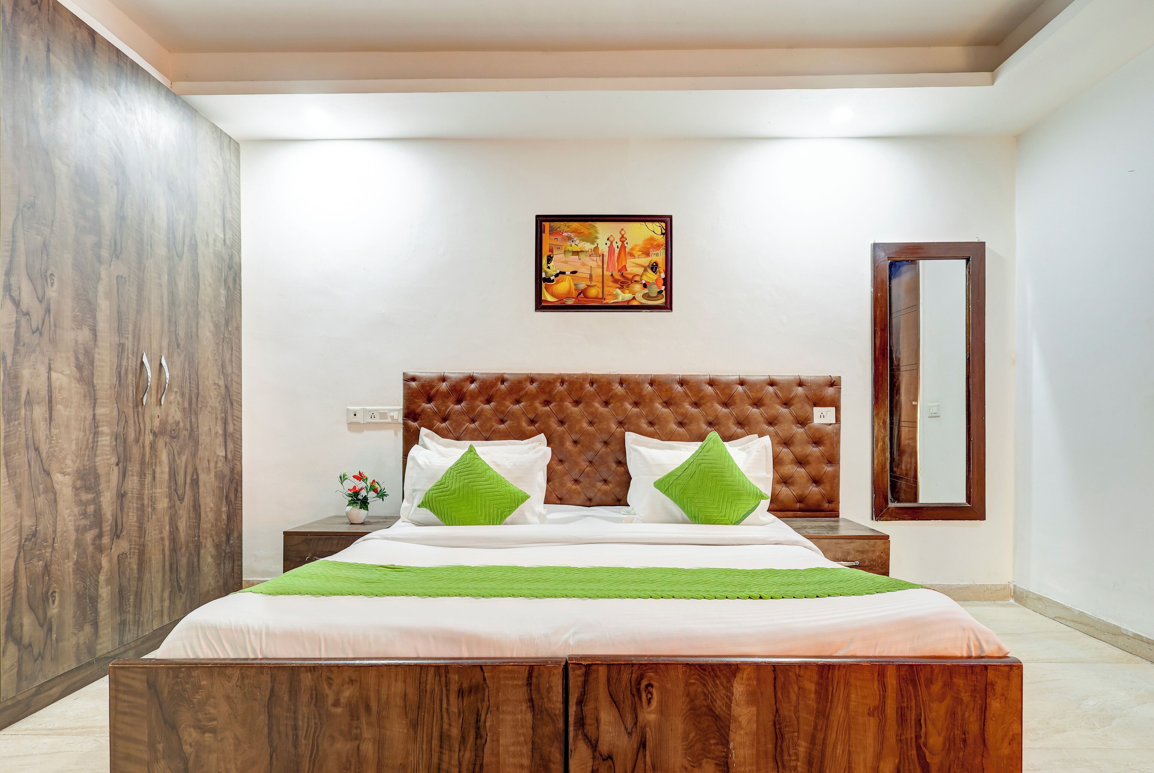 Une chambre à coucher avec un lit en bois, une tête de lit capitonnée, un tableau au mur et un miroir.