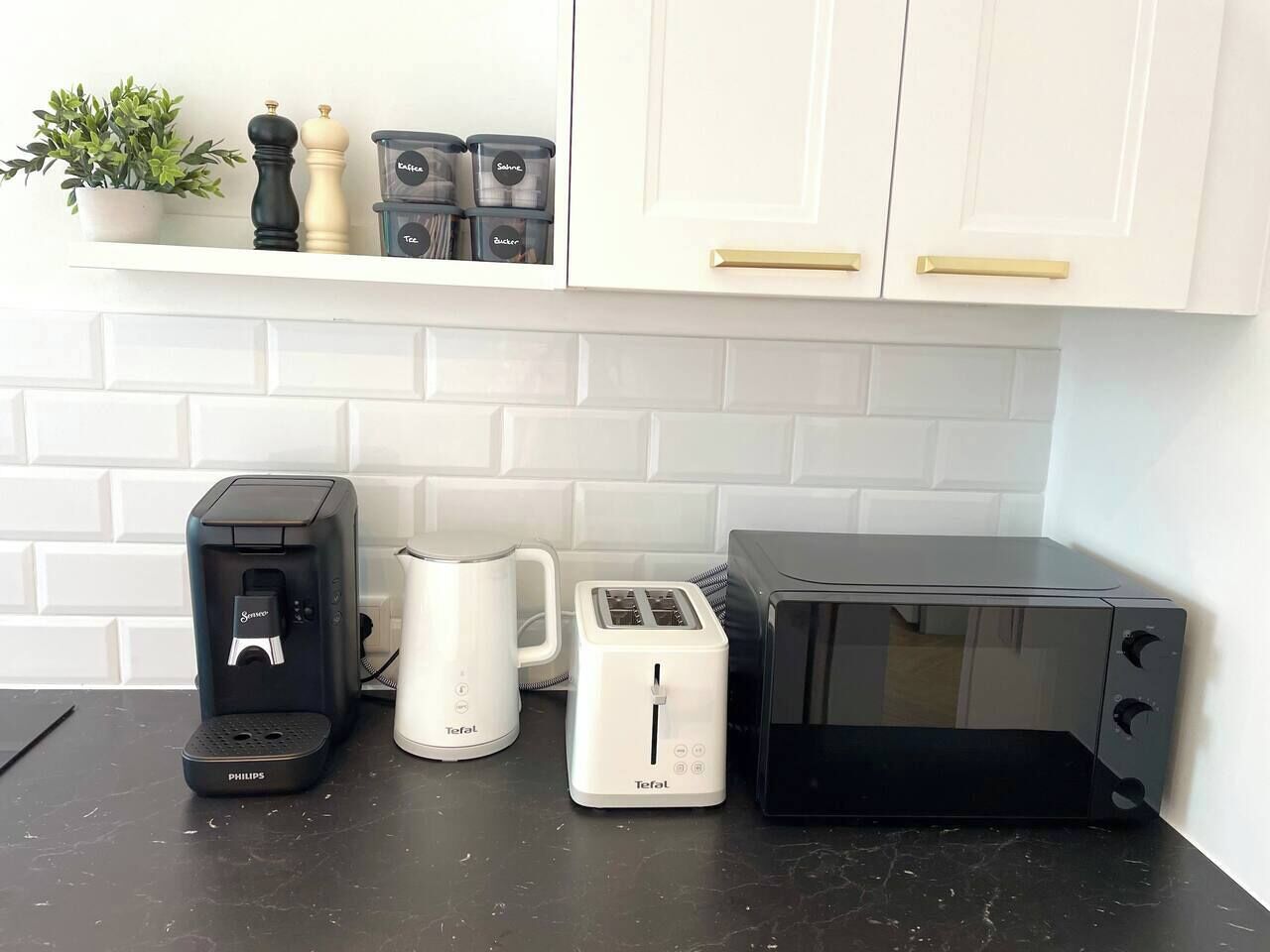 Un plan de travail de cuisine avec une machine à café, un grille-pain et un four à micro-ondes.