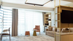 A modern living room with a sofa, armchair, and ottoman, a TV, and a bookshelf. - Lupa By Bueno (Constanta)