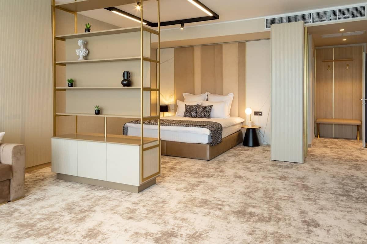 Ein modernes Schlafzimmer mit einem Bett, Nachttischen, einer eingebauten Bücherwand und einer Bank.