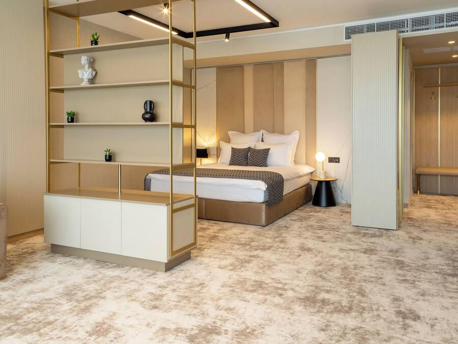 A modern bedroom with a bed, bedside tables, a built-in wardrobe, and a seating area.