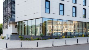 A modern building with large glass windows reflecting nearby architecture. - Lupa By Bueno (Constanta)