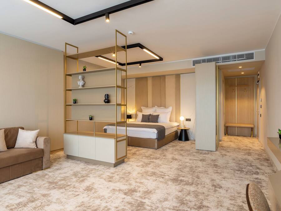 A modern bedroom with a bed, a sofa, a built-in shelving unit, and a bench.