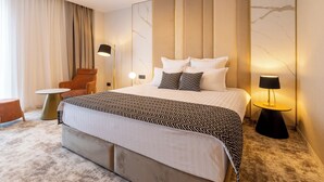 A modern hotel room with a large bed, a chair, a small table, and a lamp. - Lupa By Bueno (Constanta)