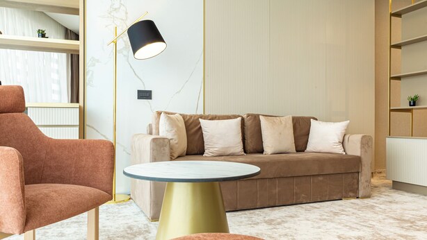A modern living room with a brown sofa, a pink armchair, and a round table. - Lupa By Bueno (Constanta)