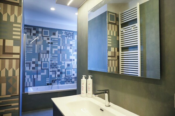 A modern bathroom with a large mirror, a bathtub, and a sink. - Una terrazza sul Golfo di Napoli by Wonderful Italy (Naples)