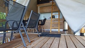 Une tente dotée d’un espace cuisine, comprenant une échelle, des chaises et une table.