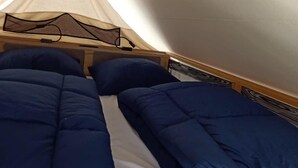 Une chambre aménagée comme une tente, avec deux lits, chacun doté de draps bleus.
