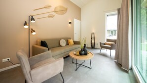 Un salon moderne comprenant un canapé, un fauteuil, une table basse et des œuvres d’art décoratives murales.
