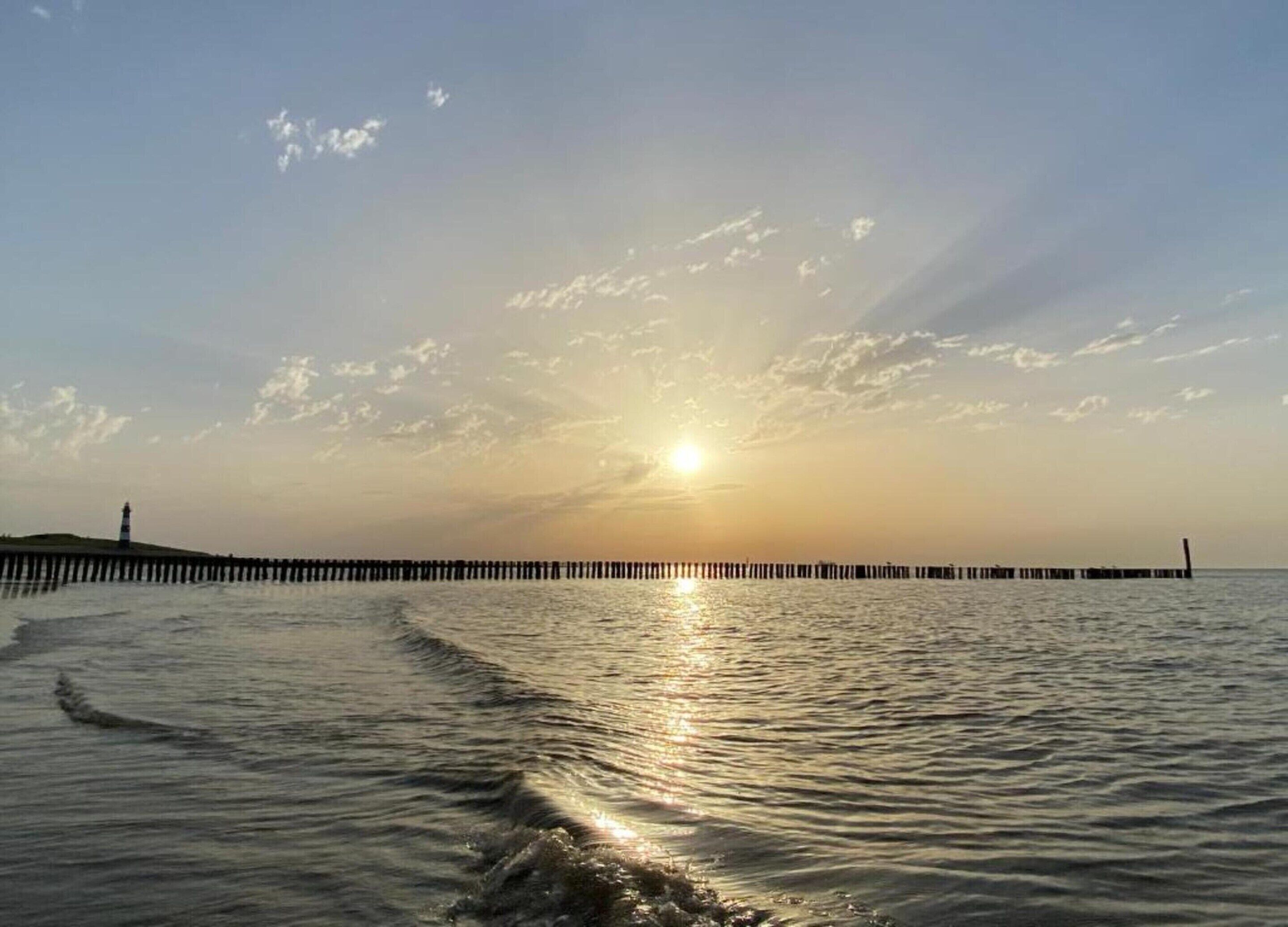 A sunset over a calm sea with a pier extending into the water.