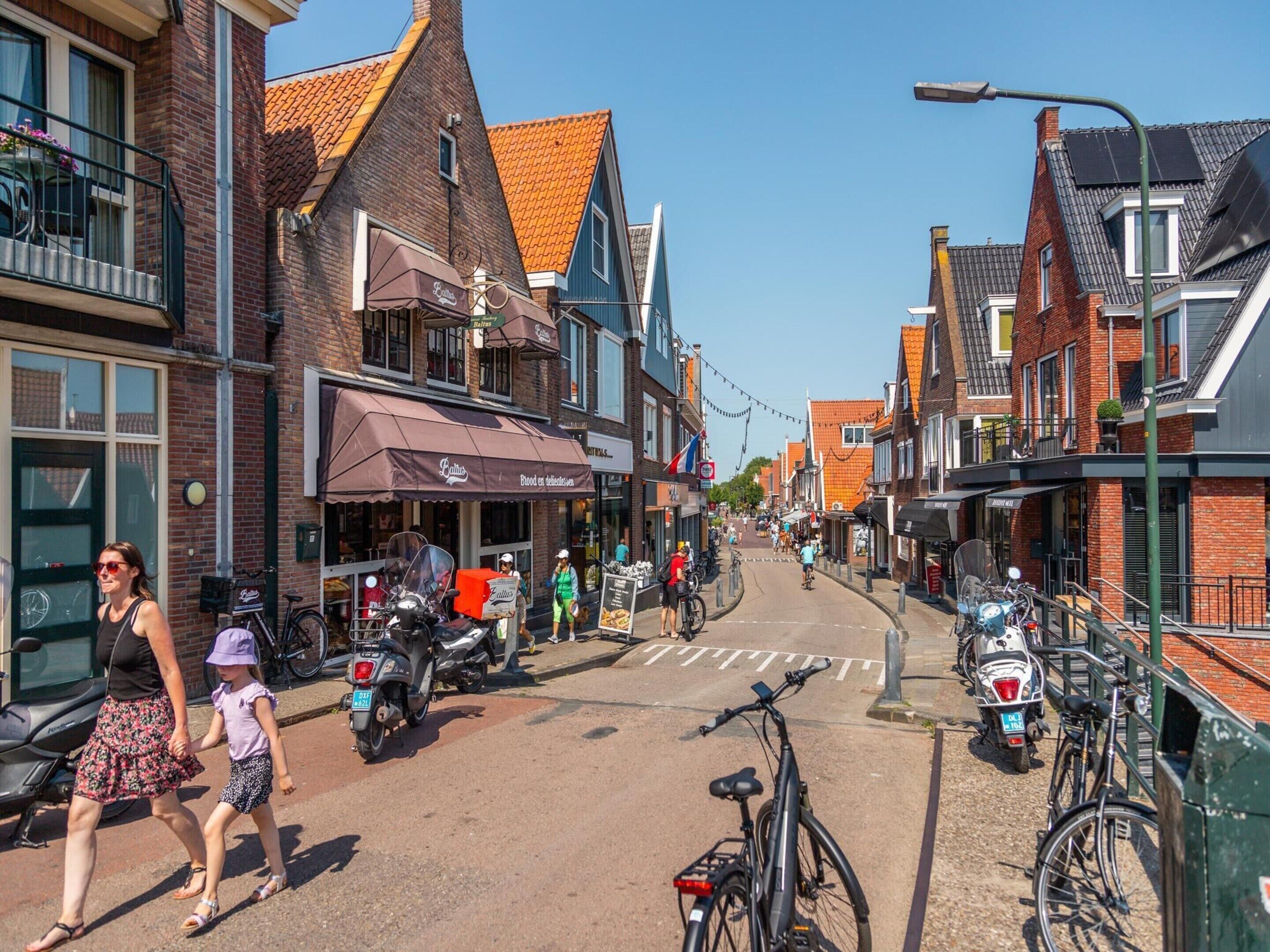 A street with buildings, a bicycle, and a person walking.