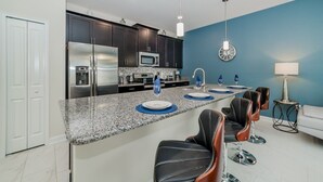 A modern kitchen with dark cabinets, stainless steel appliances, and a granite countertop.