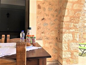 A wooden table with papers and water bottles, a stone wall, and a green chair.